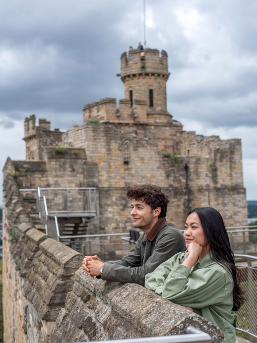 A man and a woman look out to a view from a castle