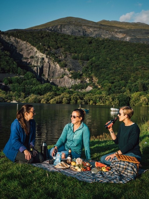 Friends having a picnic in grassland by a glacially formed lake.