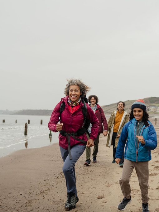 A family walking on the beach, two running ahead smiling