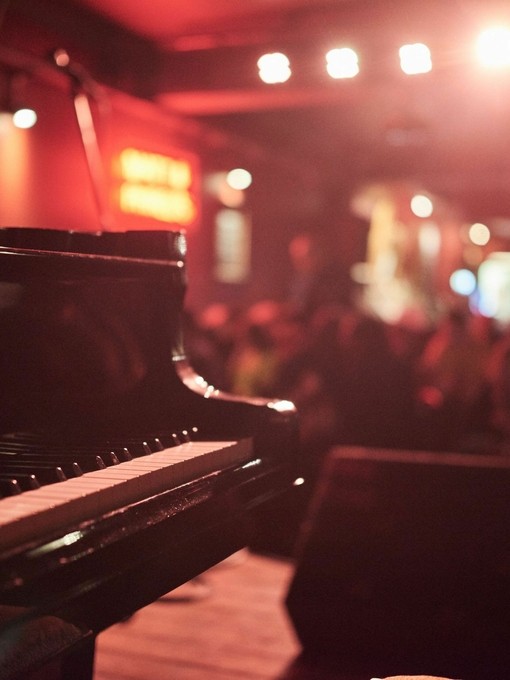 Pianist playing in a moodily lit bar. Red lighting