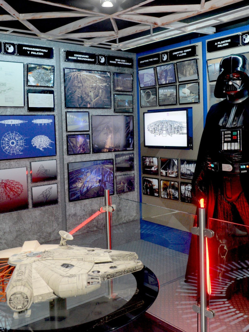 An actor in a Darth Vader costume in a Star Wars themed exhibit.