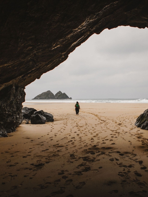 A woman walks through a cave on a beach