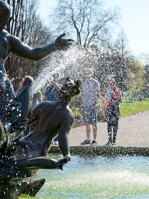 People standing in front of a fountain at a park on a sunny day