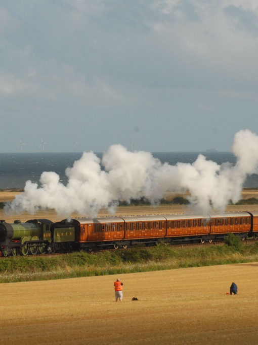 A steam train passing through fields in the Broads National Park