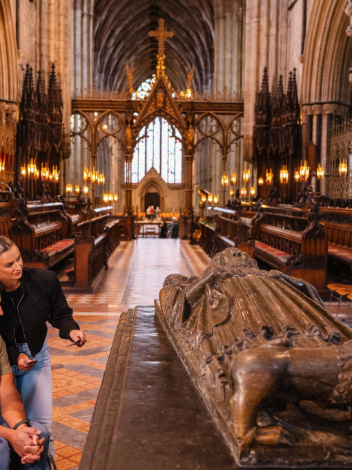A man and a woman viewing the resting place of King John buried at Worcester Cathedral
