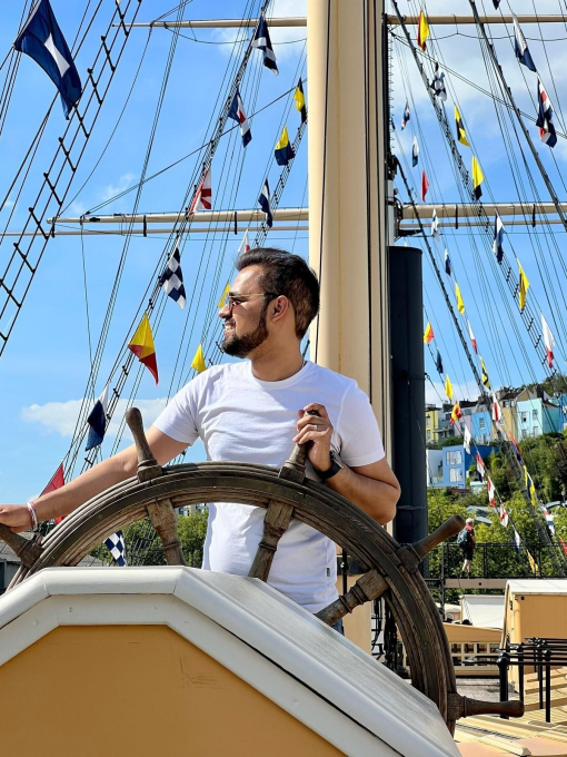 A man stood at a ship's wheel in the harbourside of Bristol