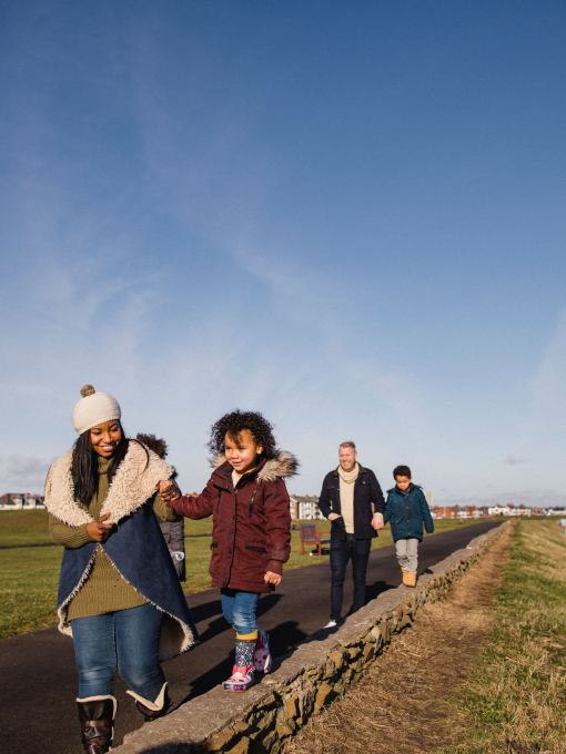 Family and friends walking along a coastal path in the winter sunshine