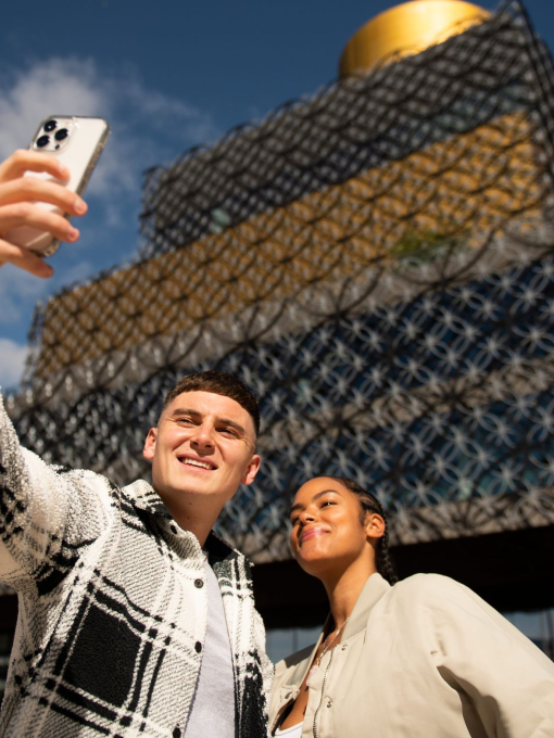 People posing for selfie in front of the Birmingham Library
