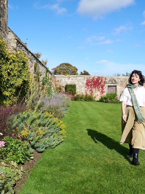 A woman walking through the gardens of a castle