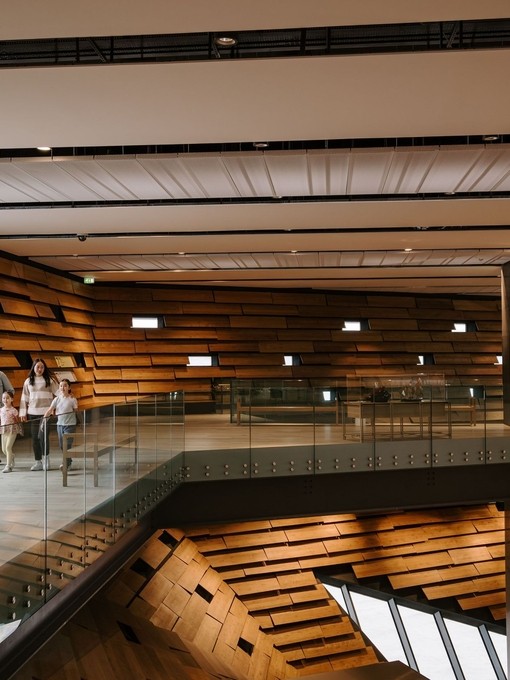 A man, a woman and two girls walking inside a modern museum.