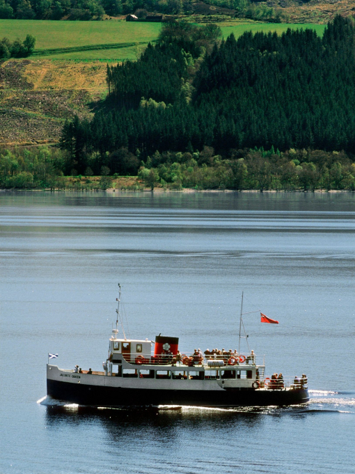 A traditional blue and white pleasure boat with a red and black funnel ferrying visitors on a lake.