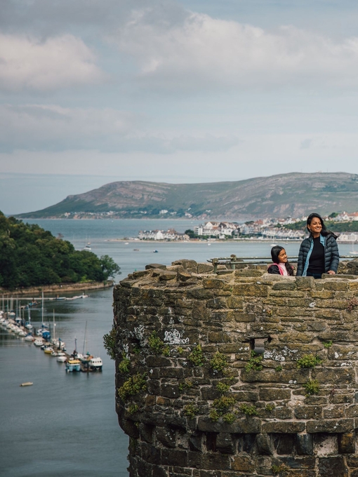 Family on top of a castle enjoying river views with boats docked and hills in the distance