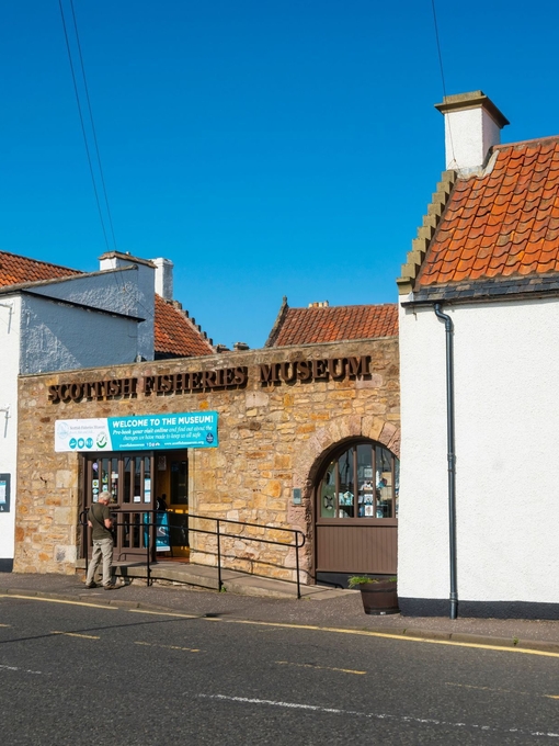 Three white houses and a brick entranceway with colourful signage on the front.