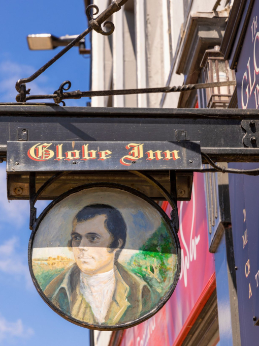 A sign for a traditional British pub that reads 'Globe Inn', with a portrait of a man.