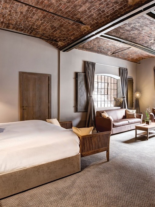 A large double bedroom with a vaulted brick ceiling and two windows.