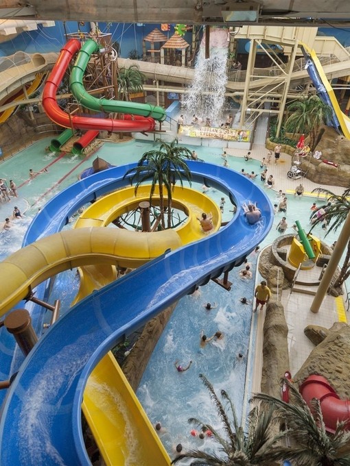 People riding slides at an indoor water park.