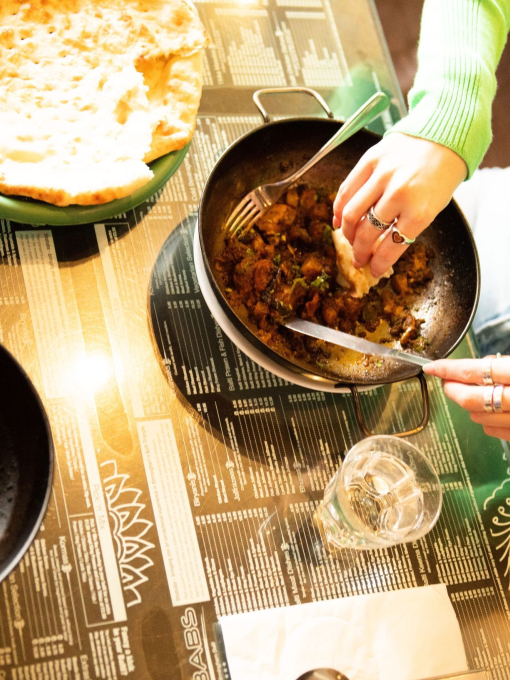 Woman sitting at table eating a curry