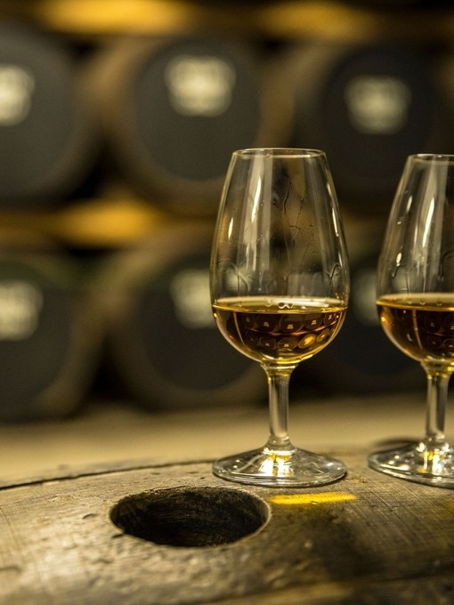 Two glasses of whisky standing on an oak barrel
