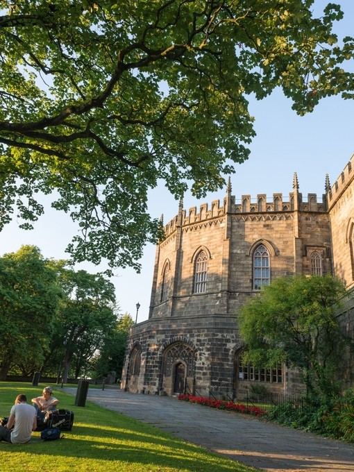 Vue extérieure du château de Lancaster avec des visiteurs assis autour de la pelouse au premier plan