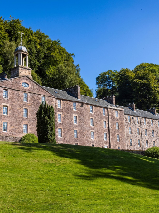 A historic four-storey mill building on a sunny day.
