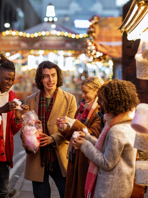 Group of young friends sharing a bag of cotton candy at the Christmas market