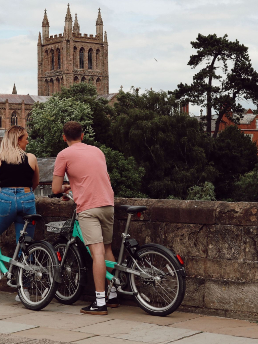 Man and woman on bikes with a cathedral in the distance