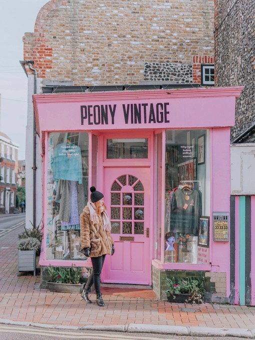 Young woman walking in front of a shop with pink signage