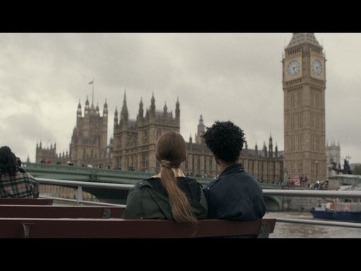 A group of people take a trip on a river boat with the Houses of Parliament beyond