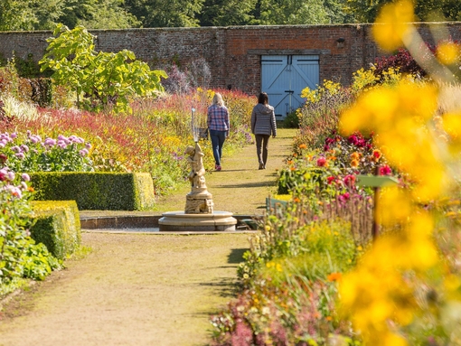 Two female friends walking through a formal garden