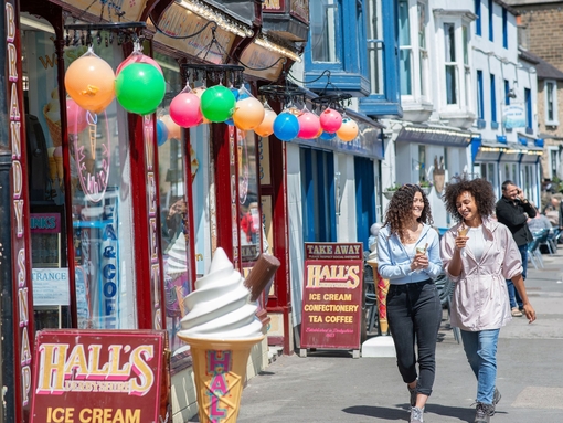Two women walk down a street with ice creams