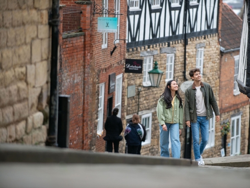 A woman and a man walk up a steep hill in a heritage City