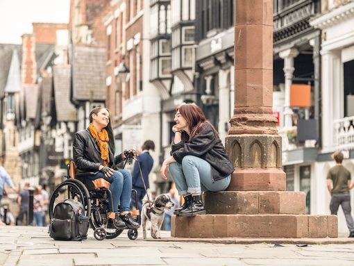 Two women sit talking together in a town centre
