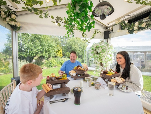 A father and two children eat lunch in a dining pod outside an Inn
