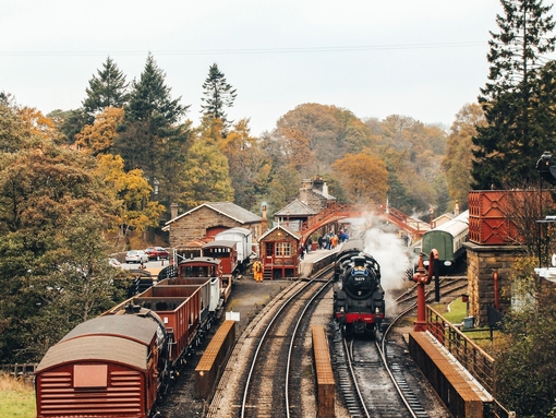 Steam train on train tracks and old-fashioned carriages at Goathland Railway Station