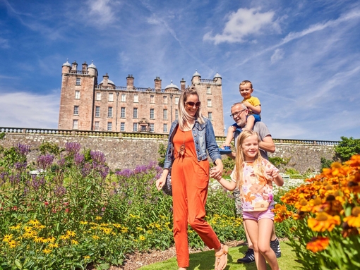 A young family walking through castle gardens.