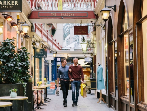 A gay couple, with arms linked, shopping indoors