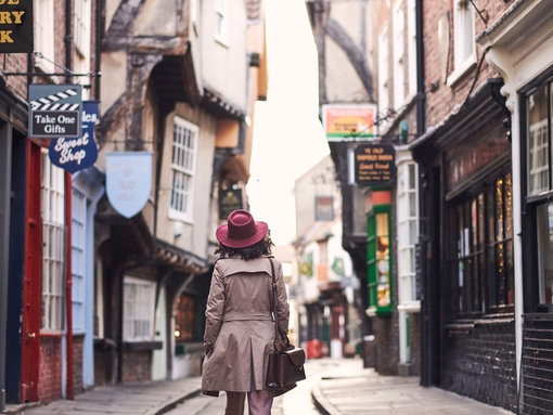 Woman wearing trench coat and pink hat walking 