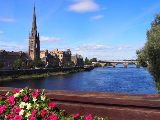 A view across a wide river to a church in the summer