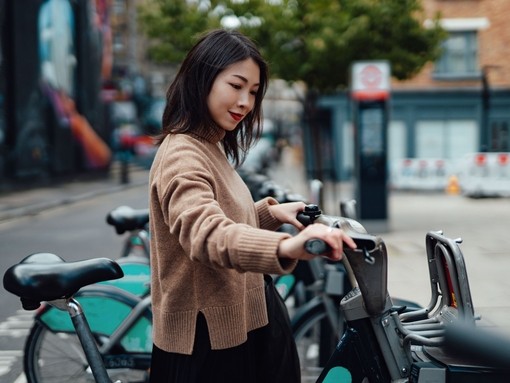 Young asian Woman Renting Bicycle From Bike Share Service