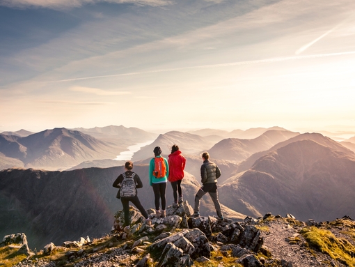 Des personnes debout sur un sommet, contemplant la vue sur les montagnes
