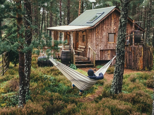 Person relaxing in hammock outside wood cabin
