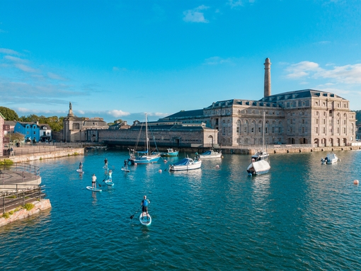 People paddleboarding near a dock in Plymouth
