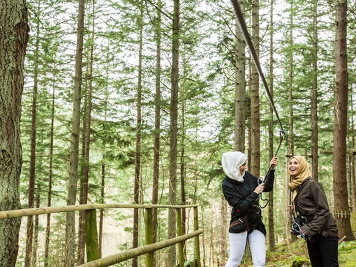 Girls standing on the zipwire platform in the pine forest
