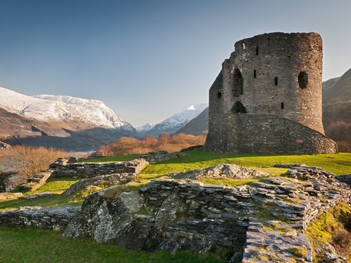 Ruins of a castle in the countryside surrounded by mountains.
