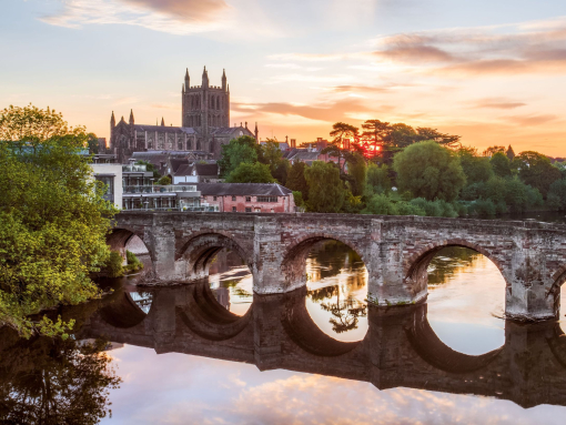 Roman Bridge over a river with a cathedral in background at sunrise