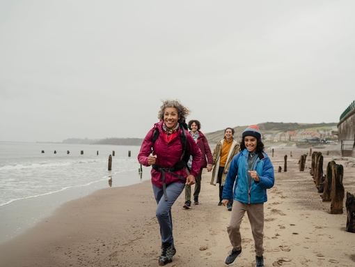 A family walking on the beach, two running ahead smiling