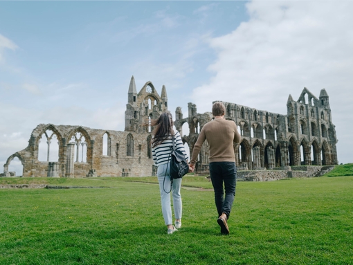 A man and woman walking towards a heritage Abbey building