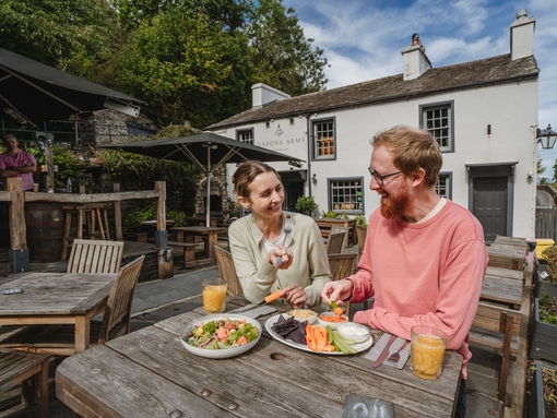 Man and woman having food whilst sitting at an outdoor table at a country pub.
