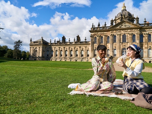 Two women enjoy scone with jam and cream in the garden of a heritage property