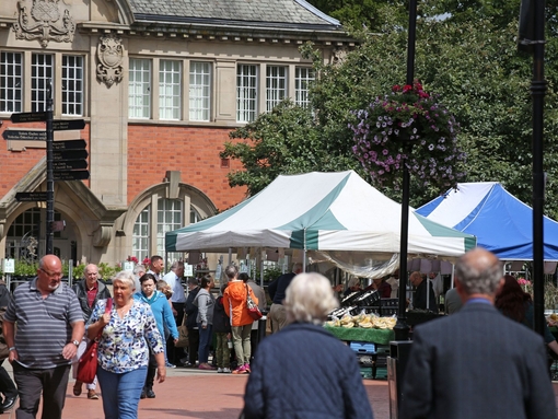 People visiting an outoor produce market near a historic building.
